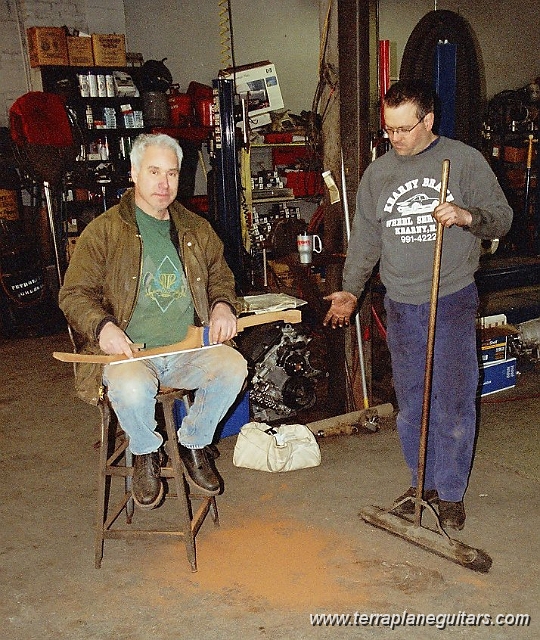 jpants.jpg - Mark hand shapes a neck for Sonny Landreth at Kearny Brake & Wheel. Joey "Pants" Correia disapproves of the mess.